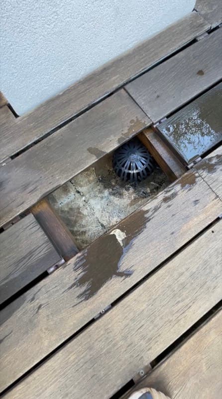 Ralo entupido sob deck de terraço com resíduos acumulados